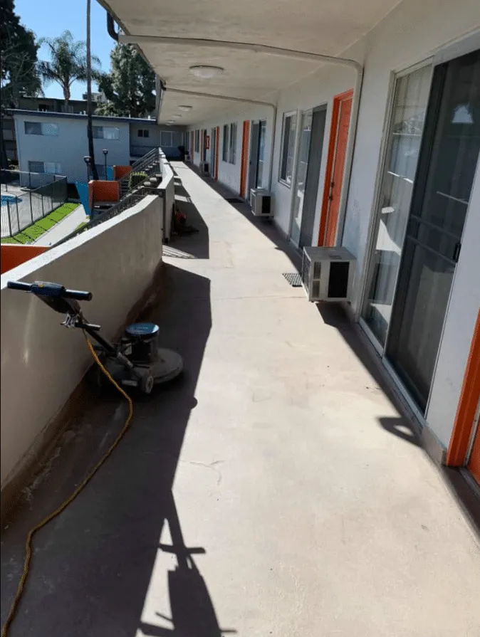Crew member operating a floor grinder on an exterior walkway