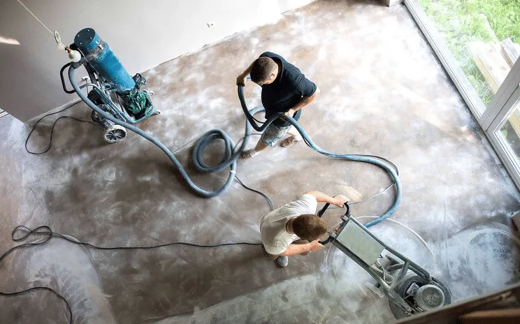 Crew grinding a concrete floor with dust-extraction equipment