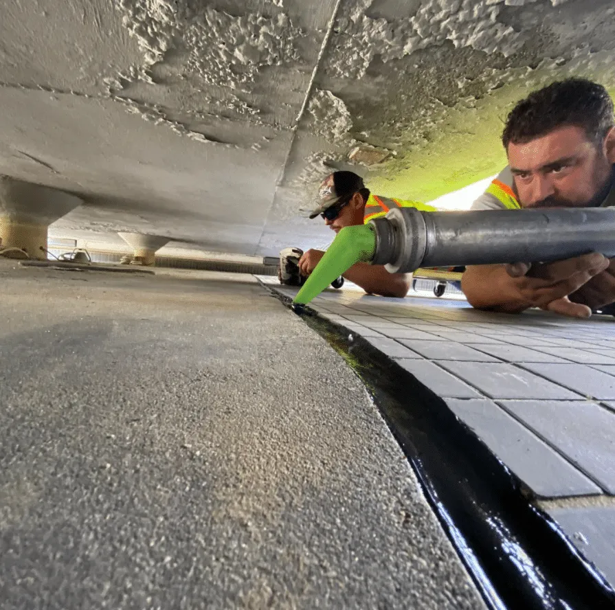 Crew member applying caulk to a concrete expansion joint