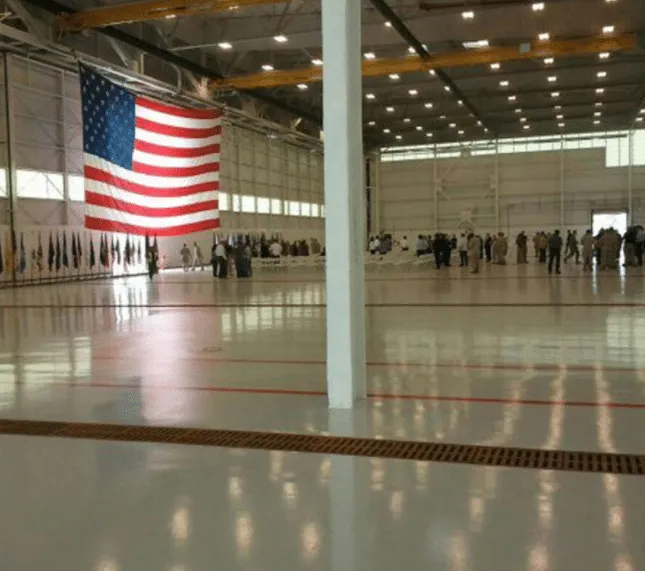 Polished floor in a large hangar-style facility with an American flag on the wall