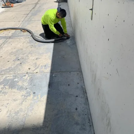 Worker grinding concrete along a wall edge