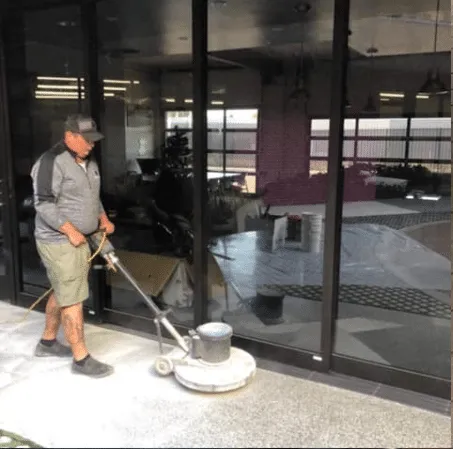Worker operating a floor buffer near glass doors