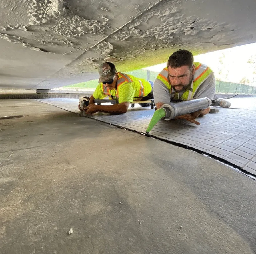 Crew members applying caulking to a concrete joint